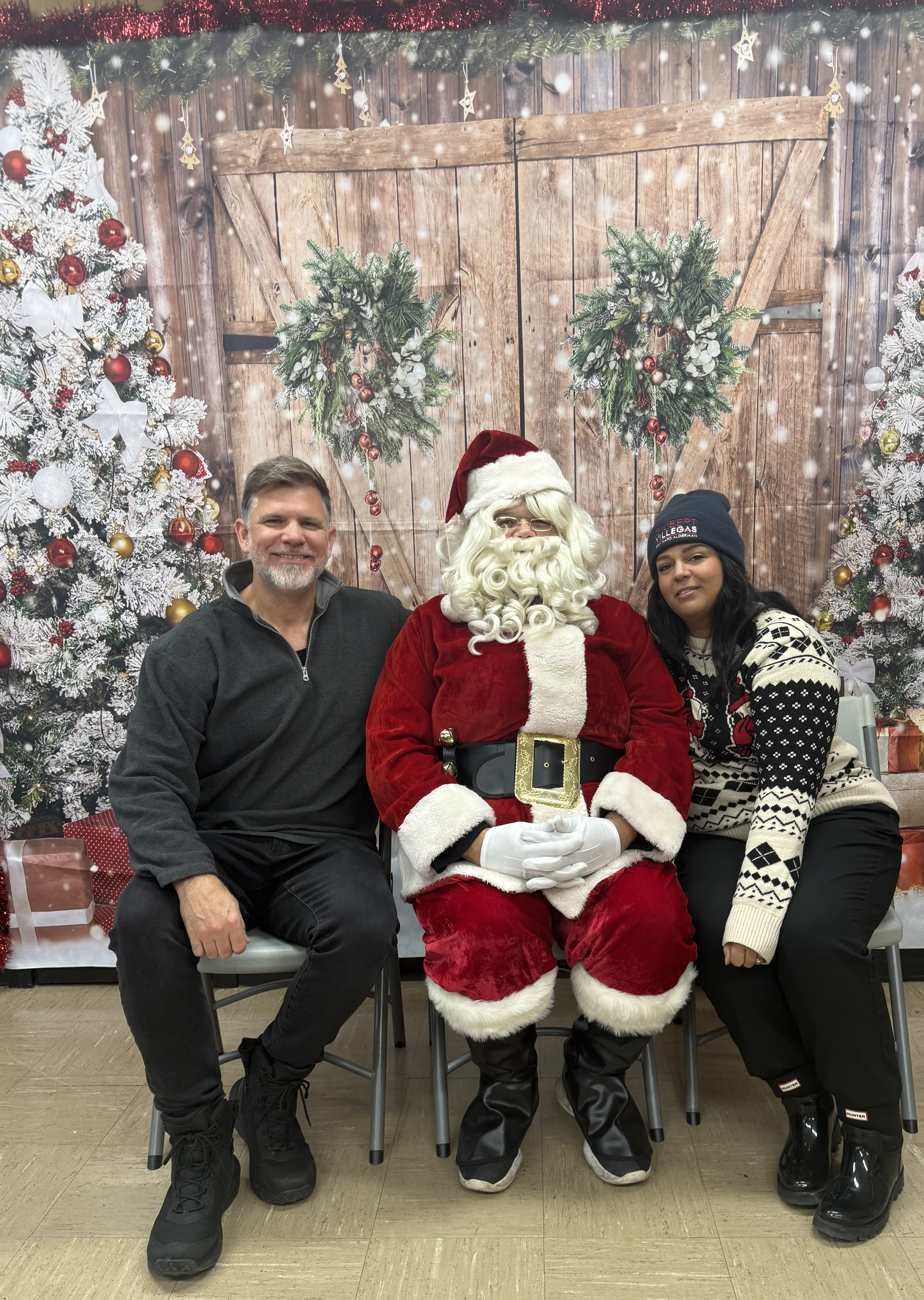 Photograph of Santa posing with a smiling man and woman.